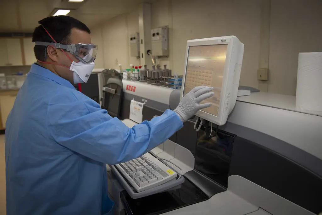 Lab technician running an analysis on an instrument touchscreen